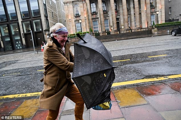 A shopper struggles to hold an umbrella due to strong wind as Storm Eowyn hit in Edinburgh
