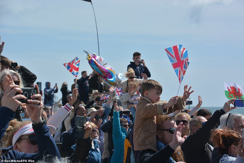 Families, many carrying Union Flags or holding banners, cheered and waved as HMS Prince of Wales set sail