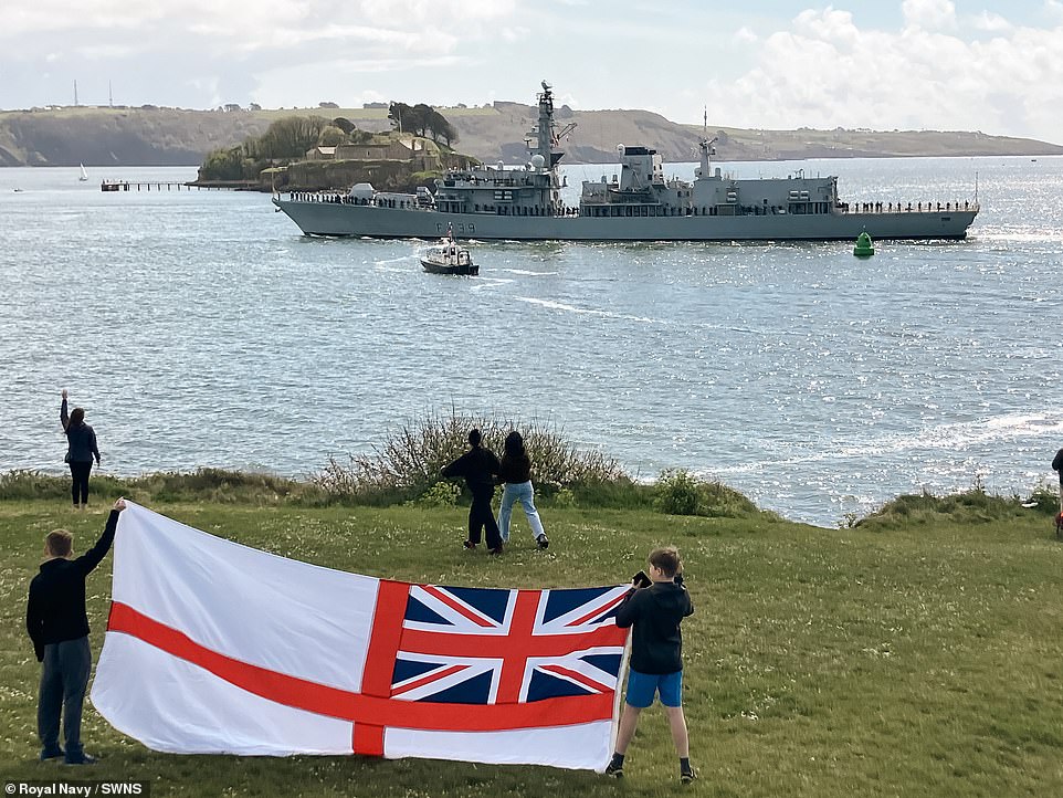 Two young boys proudly hold a White Ensign flag aloft as HMS Richmond departed its home in Plymouth on Tuesday