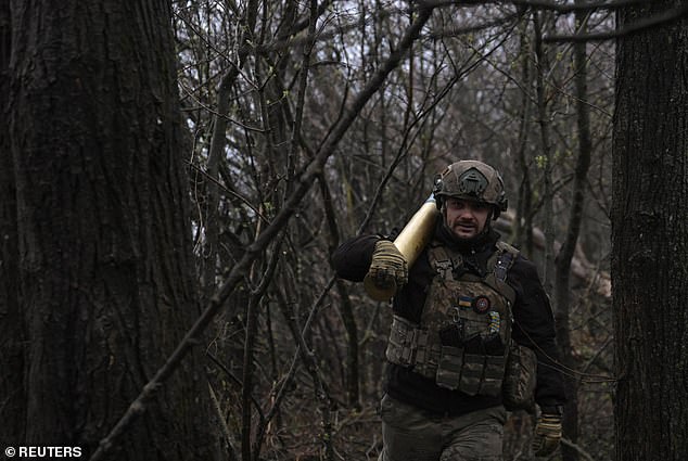 A Ukrainian serviceman of the 108th Territorial Defence Forces Brigade carries an artillery shell at a frontline position, amid Russia's attack on Ukraine, in Zaporizhzhia region