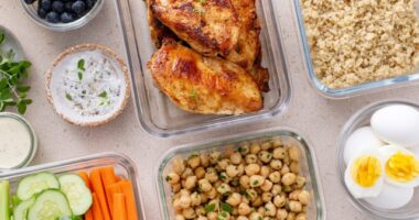 high protein meal prep concept with chicken chickpeas quinoa hard boiled eggs veggie sticks and blueberries in individual containers