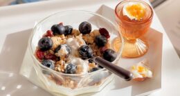 bowl of yogurt with berries and granola with an egg