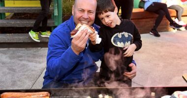 Treasurer Josh Frydenberg enjoys a sausage with son Blake after voting on Saturday