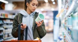 woman reading a food label while grocery shopping