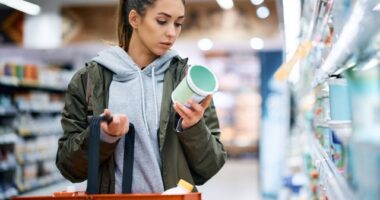 woman reading a food label while grocery shopping