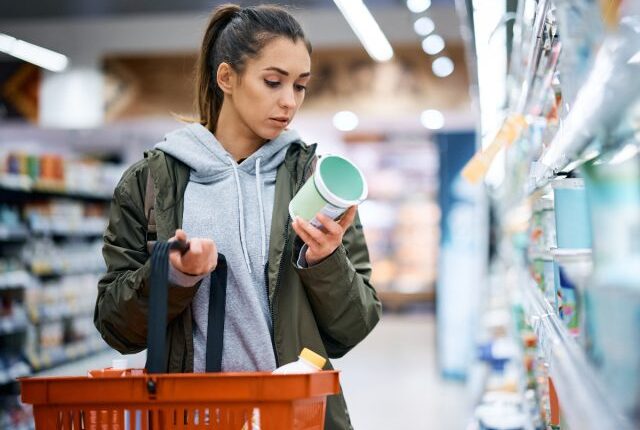 woman reading a food label while grocery shopping