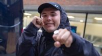Kneecap rapper poses at surprise performance which Irish trio announced just hours after member was charged with terror offence 'for displaying flag in support of Hezbollah'