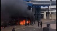 'Anti-migrant' tensions come to a head in Northern Ireland as leisure centre sheltering families who fled Ballymena chaos is set on fire - while riot police battle yobs and terrified locals put up signs showing their nationality