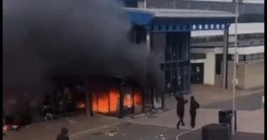 'Anti-migrant' tensions come to a head in Northern Ireland as leisure centre sheltering families who fled Ballymena chaos is set on fire - while riot police battle yobs and terrified locals put up signs showing their nationality