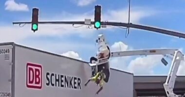 Horror moment worker is smashed into by huge 18-wheeler leaving him dangling from basket upside down above busy road